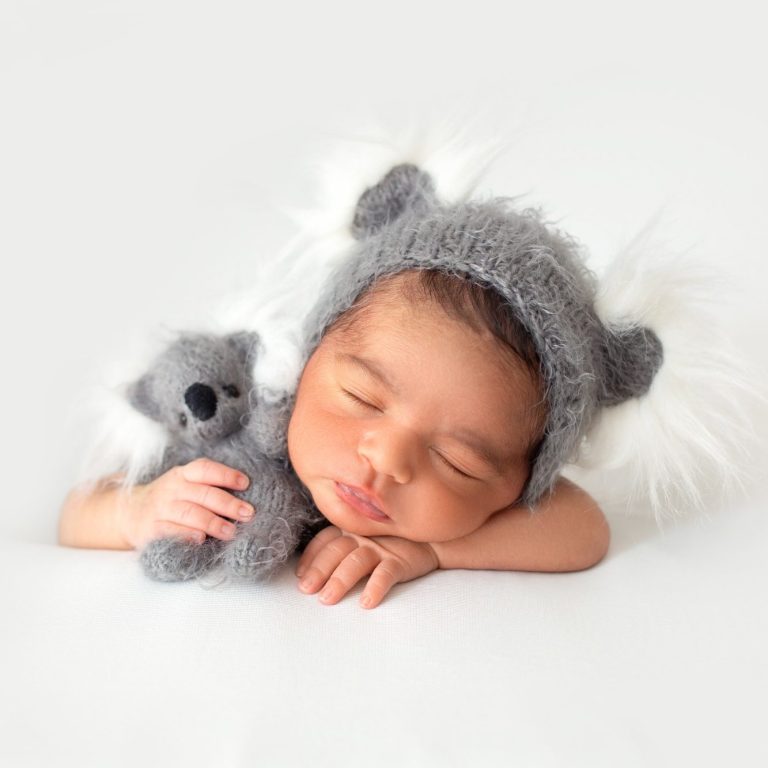 Resting newborn in little cute grey hat and with grey toy bear in his hands
mdjaff